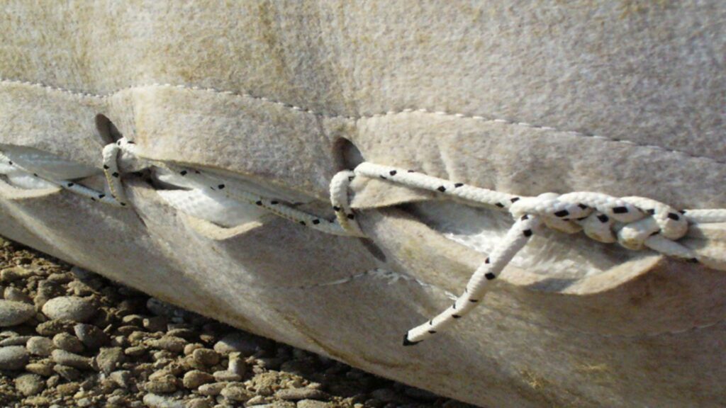Close-up view of UV-stabilized, sand-filled geotextile bag used in riverbank protection